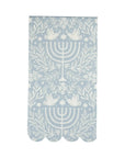 The MME Napkin by Faire is adorned with a light blue and white symmetrical design, showcasing doves, menorahs, floral patterns, and stars. It also features scalloped edges.