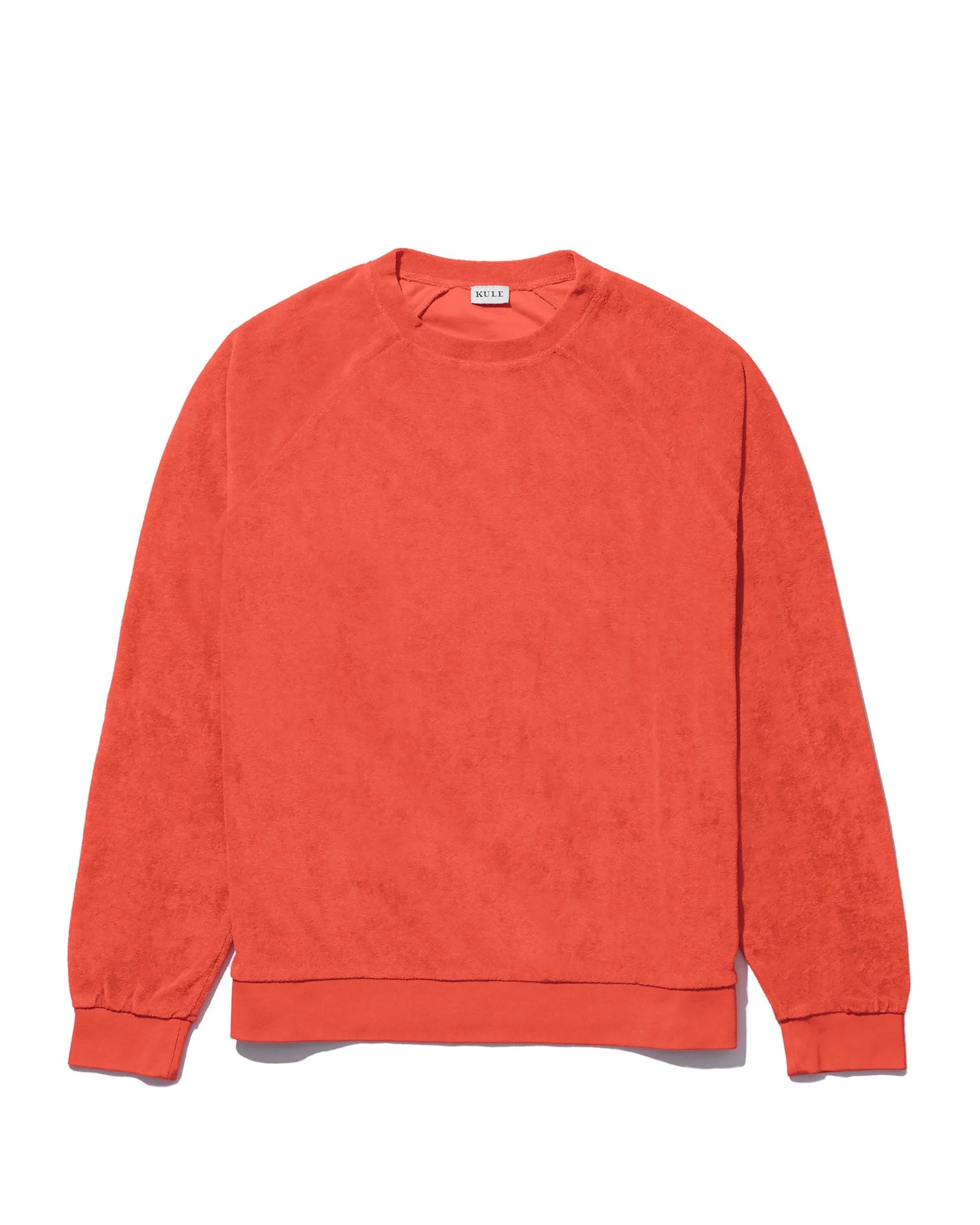 The Terry Franny sweatshirt by Kule is an oversized, long-sleeve crewneck in a vibrant solid orange, crafted from a soft, textured cotton-blend fabric and shown laid flat on a white background.