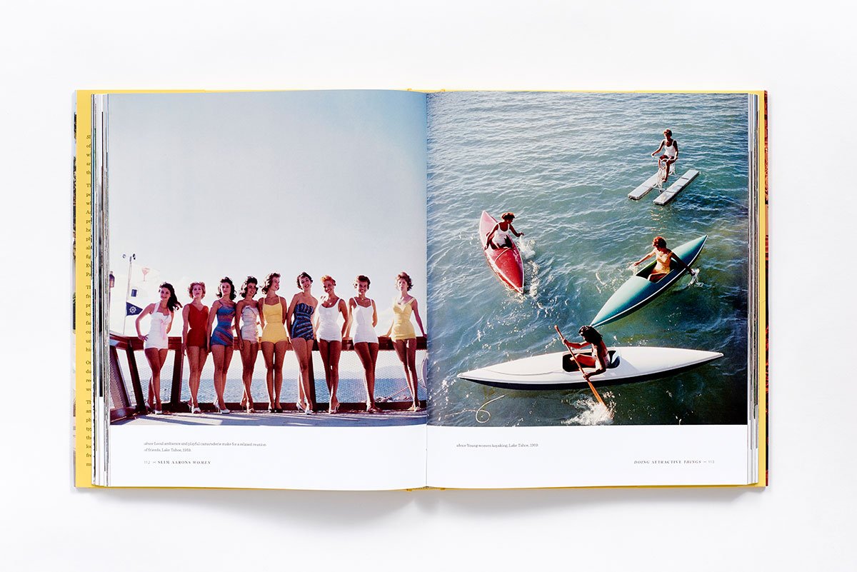 An open book, "Slim Aarons: Women" by Hachette Book Group, displays vintage photos: on the left, elegant women in swimsuits pose on a dock; on the right, people paddle boats and canoes under sunny skies.