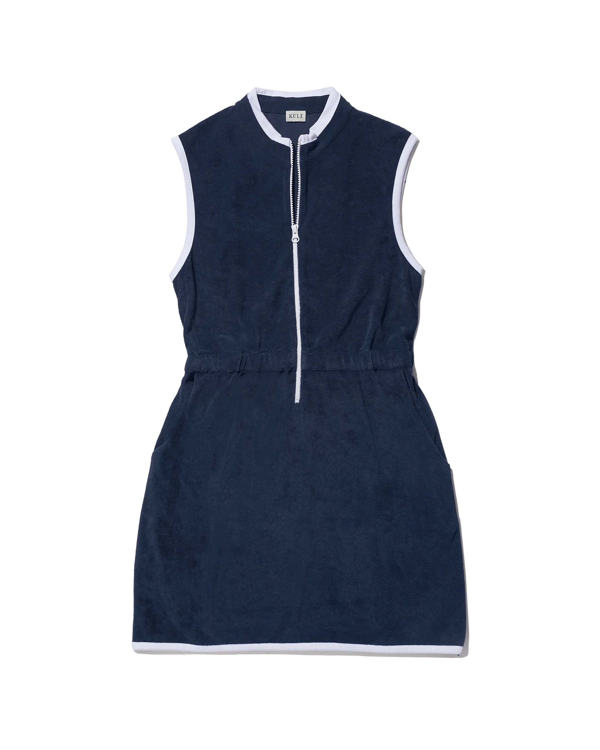 The Kule Terry Dress is a sleeveless navy blue summer dress with white trim, front zipper, elastic waistband, small stand-up collar, and side pockets, shown laid flat on a white background.