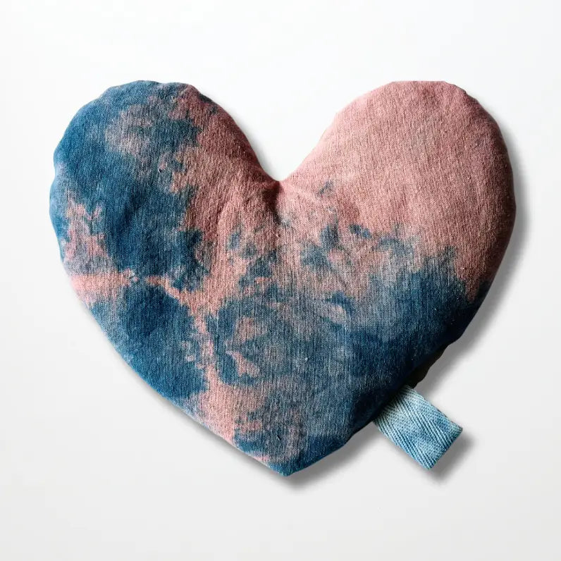The Faire Heart Eye Pillow, featuring a pink and blue tie-dye cotton design with a small blue fabric loop, provides gentle anxiety relief and is displayed against a plain white background.