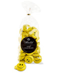 Yellow foil-wrapped chocolates with smiley faces are in a clear plastic bag labeled "Abdallah." The bag specifies "Milk Chocolate Bags," and one solid chocolate is outside the bag.