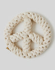 A beige, braided Peace Sign Dog Toy from Faire, made of rough natural fibers, shaped into a peace symbol against a plain light background, promotes animal welfare through mindful design.