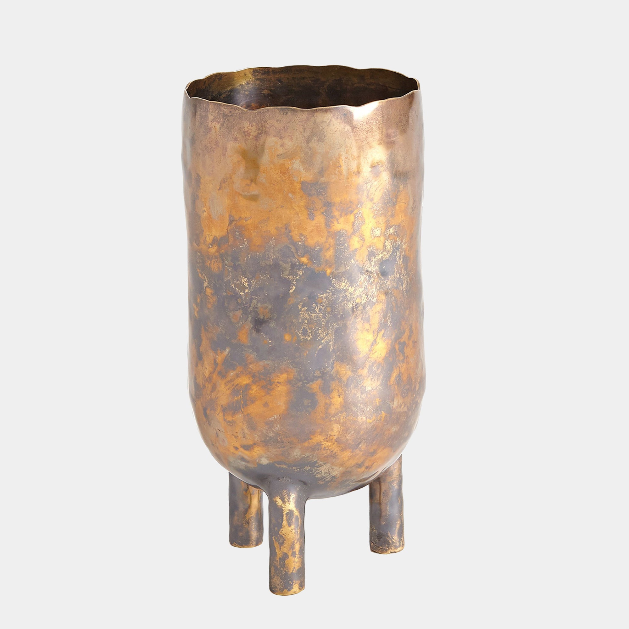 The Alchemy Container Burnt Brass T by Global Views is a tall, cylindrical metallic vase with a mottled gold and bronze oxidized brass finish, wavy rim, and three short rounded legs, shown against a plain light background.