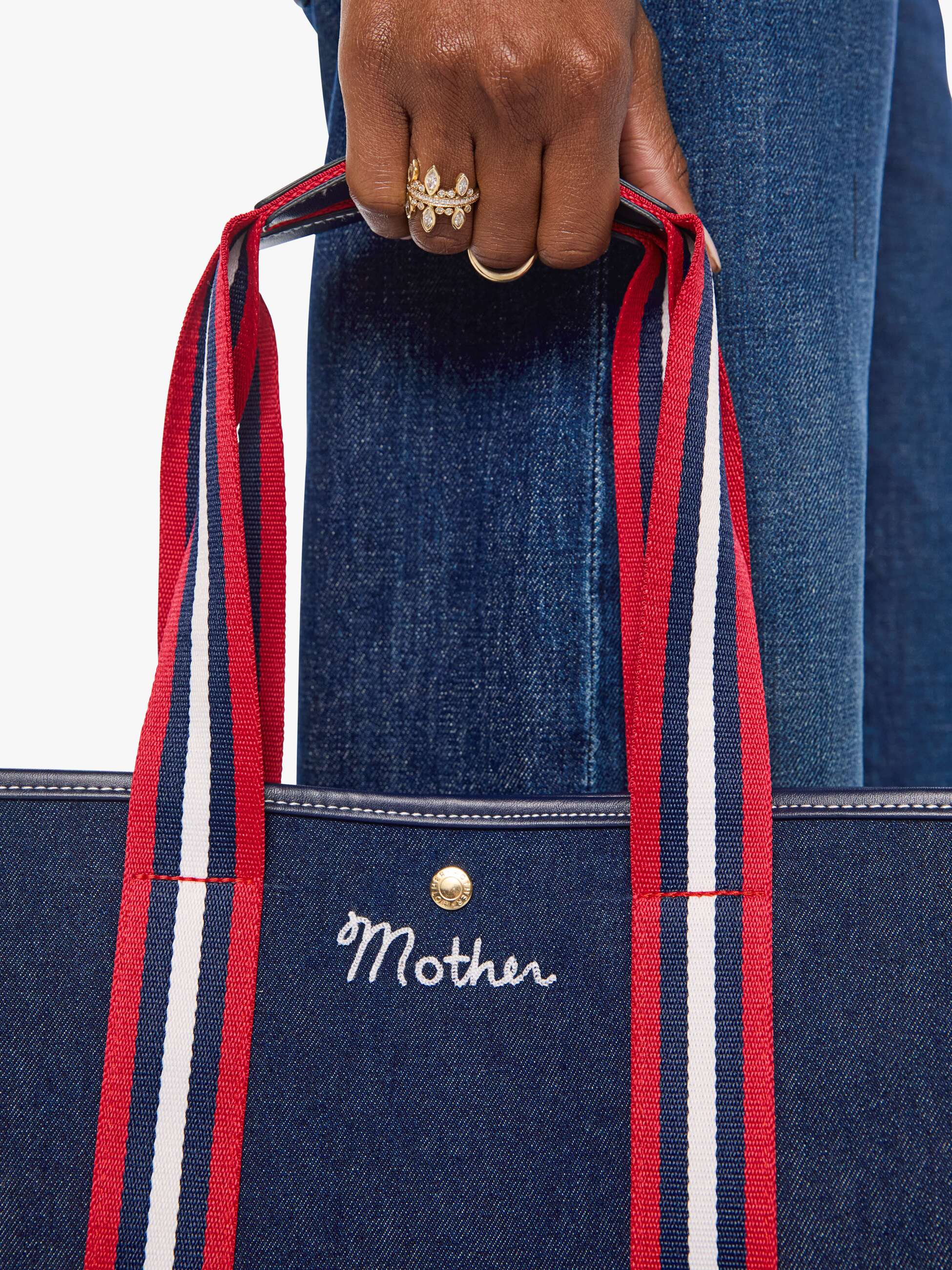 The Everywhere denim tote by Mother with red, white, and blue handles, styled with casual blue jeans.