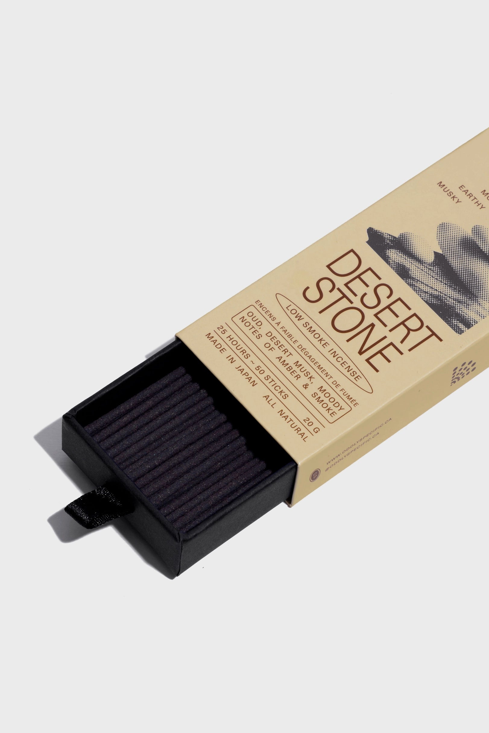 A beige box labeled "Desert Stone" from Faire’s Low Smoke Incense reveals black incense sticks, made from natural ingredients, partially slid from a black inner tray. The minimalist packaging features subtle cloudy designs and clean text.
