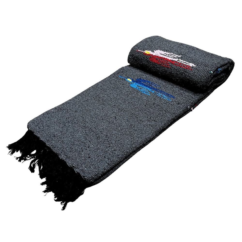 The Charcoal Thunderbird Baja Blanket by Faire is a handmade gray woven blanket with black fringe and two embroidered horses—one red, one blue—near the top edge, inspired by classic Mexican Thunderbird blanket designs.
