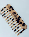 The Faire Hair Comb Assorted is a medium acetic acid comb with a tortoiseshell pattern in brown and black on beige, displayed on a plain white surface.