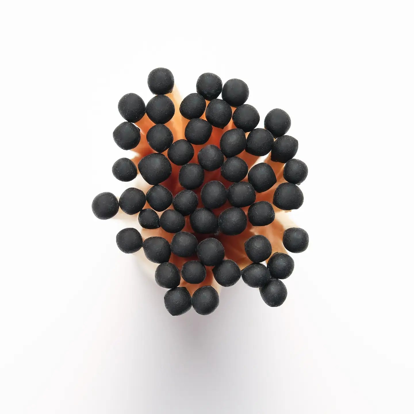 A close-up, top-down view of Faire’s Fireplaces Apothecary Matches shows their black match heads clustered together against a white background.