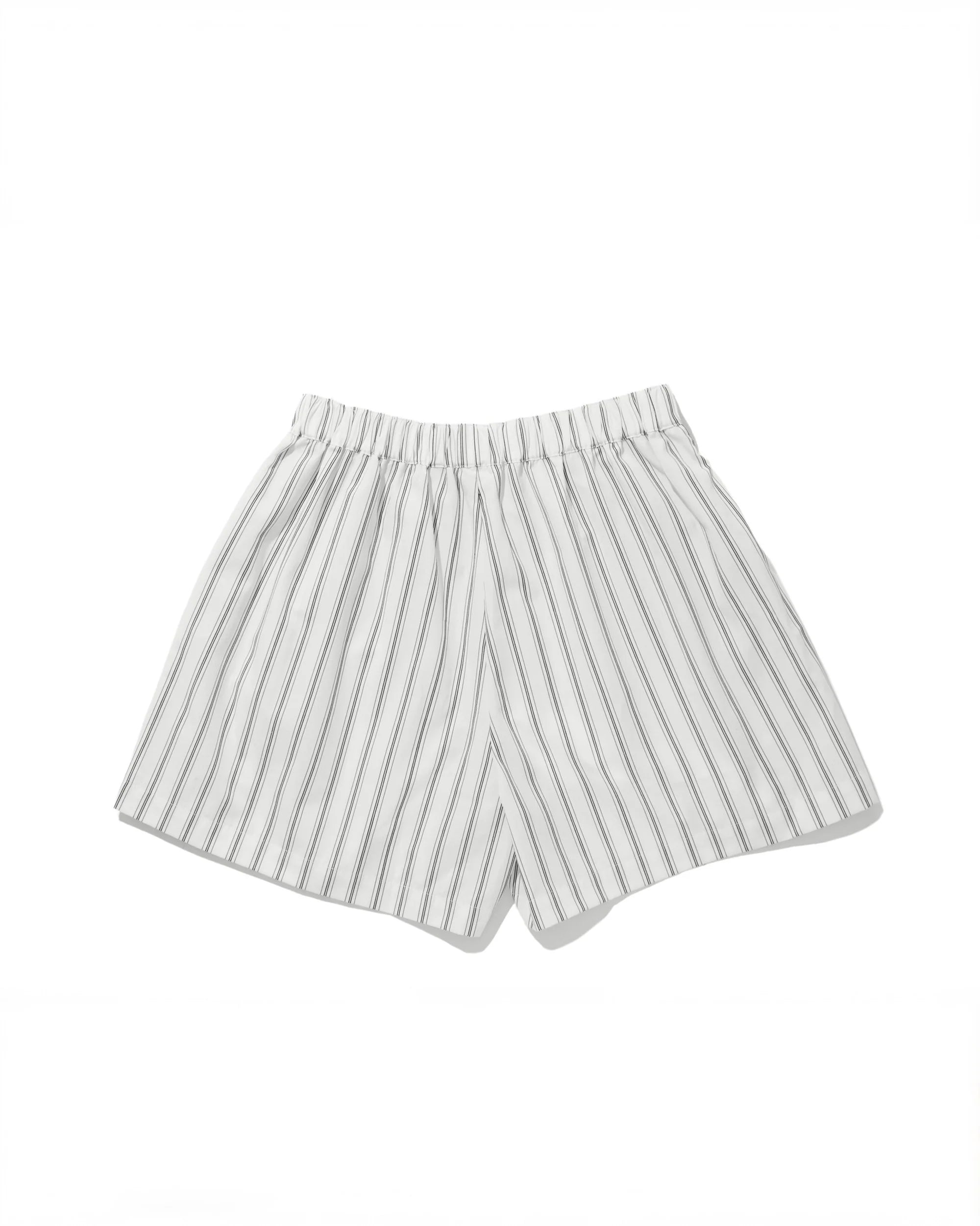 The Limon by Kule: white cotton shorts with vertical black pinstripes and an elastic waistband, shown on a plain white background—ideal for vacation-ready looks.