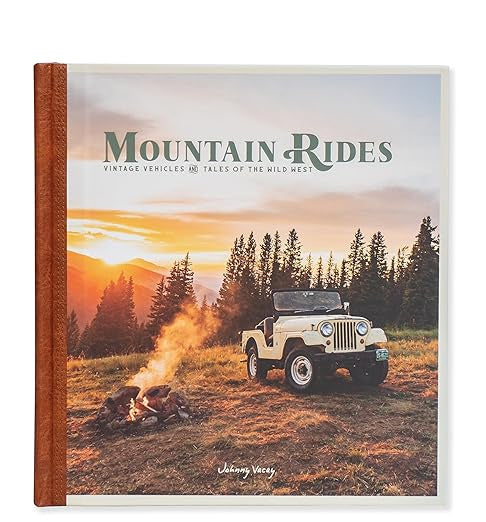 Cover of the "Mountain Rides Book" by Faire, featuring a classic Jeep—an iconic vintage 4x4—positioned on a grassy area with a campfire, enveloped by trees and mountain towns at sunset.