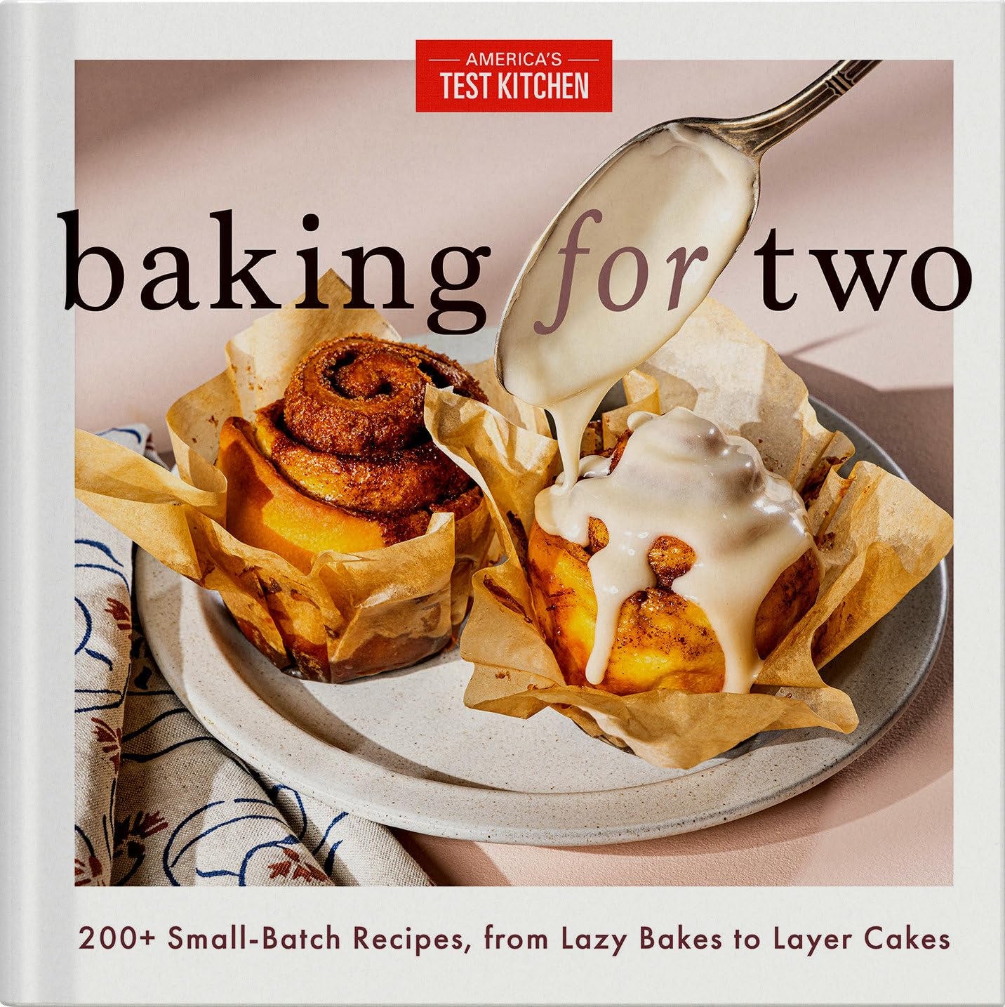 Cover of "Baking for Two" by Random House. It features two cinnamon rolls on parchment; one is being drizzled with icing. The text promises over 200 big-flavor recipes, from simple bakes to layer cakes, using innovative techniques for small-batch baking.