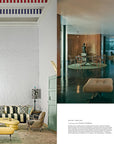 Inspired by Hachette Book Group’s "Architectural Digest at 100," this living room features patterned sofas and yellow ottomans alongside a modern glass-walled space, capturing the elegant style of celebrity homes.