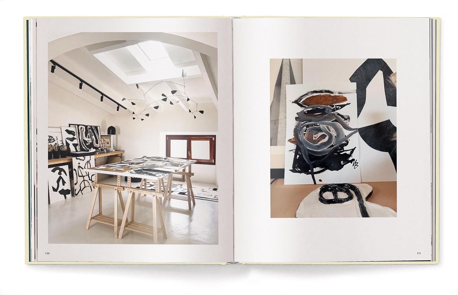 An open copy of "Creating A New Home In Mallorca" by Ingram Book Company displays Malene Birger’s bright studio with abstract black and white art on the left page and a close-up of a black, white, and brown painting on the right.