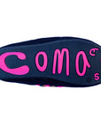 The bottom of a dark-colored lounge slipper by Faire features bright pink, raised letters spelling "Coma Toes" in a playful, irregular font on the sole.
