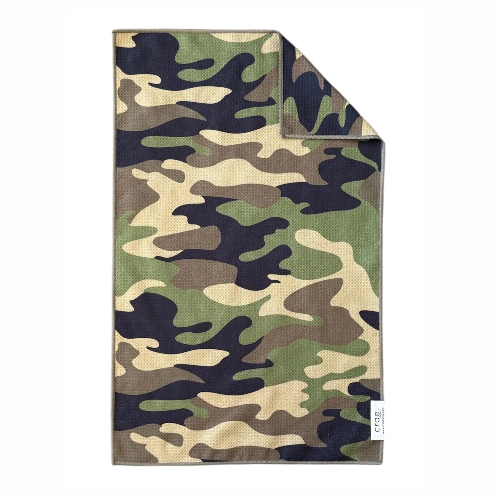 The Faire Double Sided Hand Towel features a high-absorbent waffle weave microfiber in a green, brown, black, and tan camouflage pattern. A corner is folded to show the reverse side and a small white label with text.