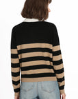 A person with shoulder-length brown hair is facing away, wearing a Rugby Stripe Polo by Minnie Rose along with light blue jeans. Ideal for casual and semi-formal occasions, the black and tan stripes stand out against the plain white background.