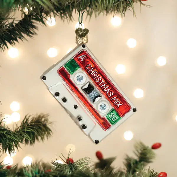 The Old World Ornaments by Faire features a cassette tape labeled "A Christmas Mix," hanging among assorted decorations on a lit tree branch.