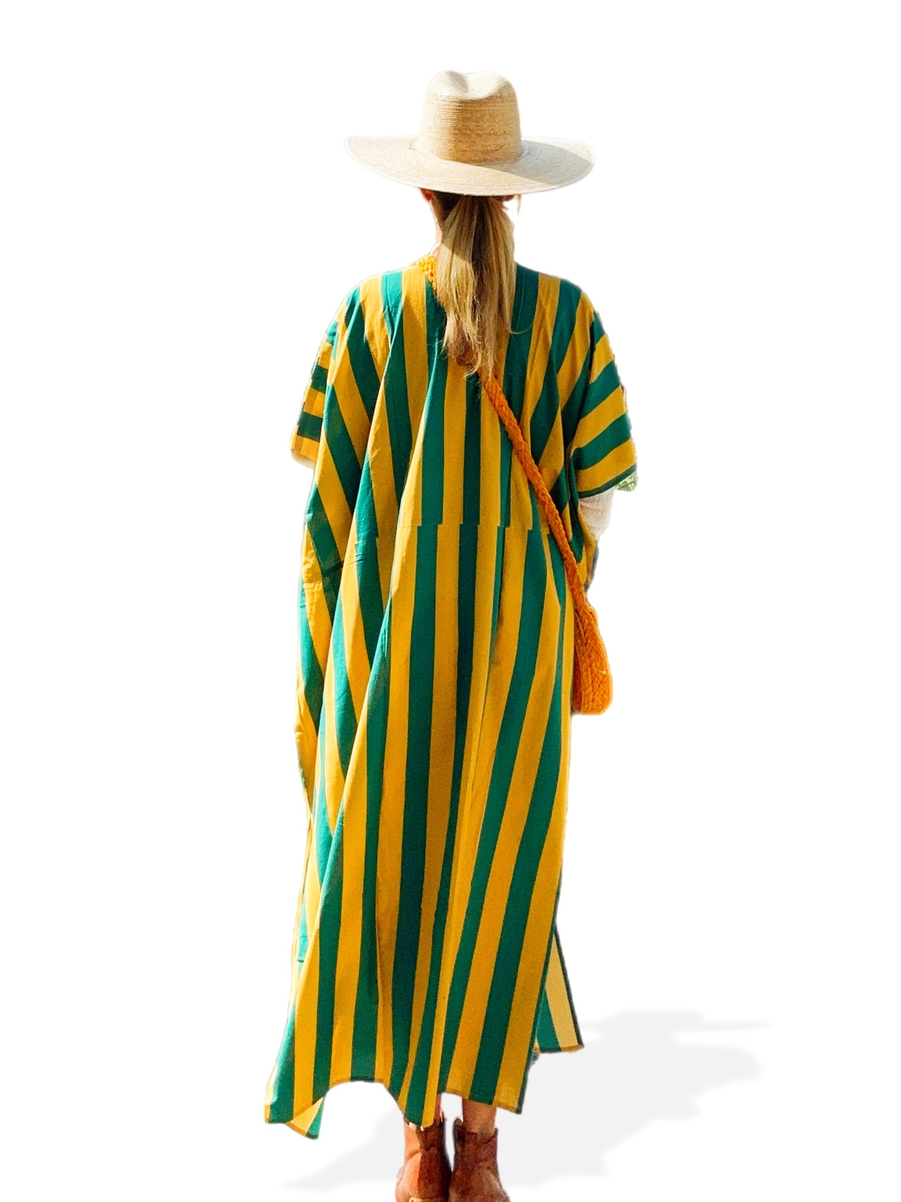 A person wearing a wide-brimmed hat and a loose Faire Surf Stripe Kaftan stands facing away, with a brown crossbody bag and brown shoes, against a white background.