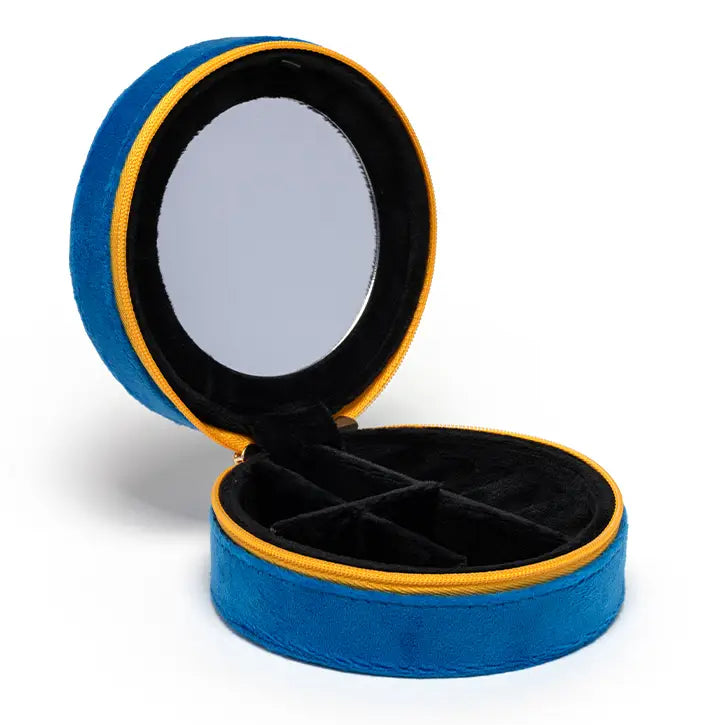 The Caviar Jewelry Case is a round blue velvet organizer with a yellow zipper, featuring a mirror in the lid and black divided compartments—perfect as a stylish jewelry box or a compact travel case.