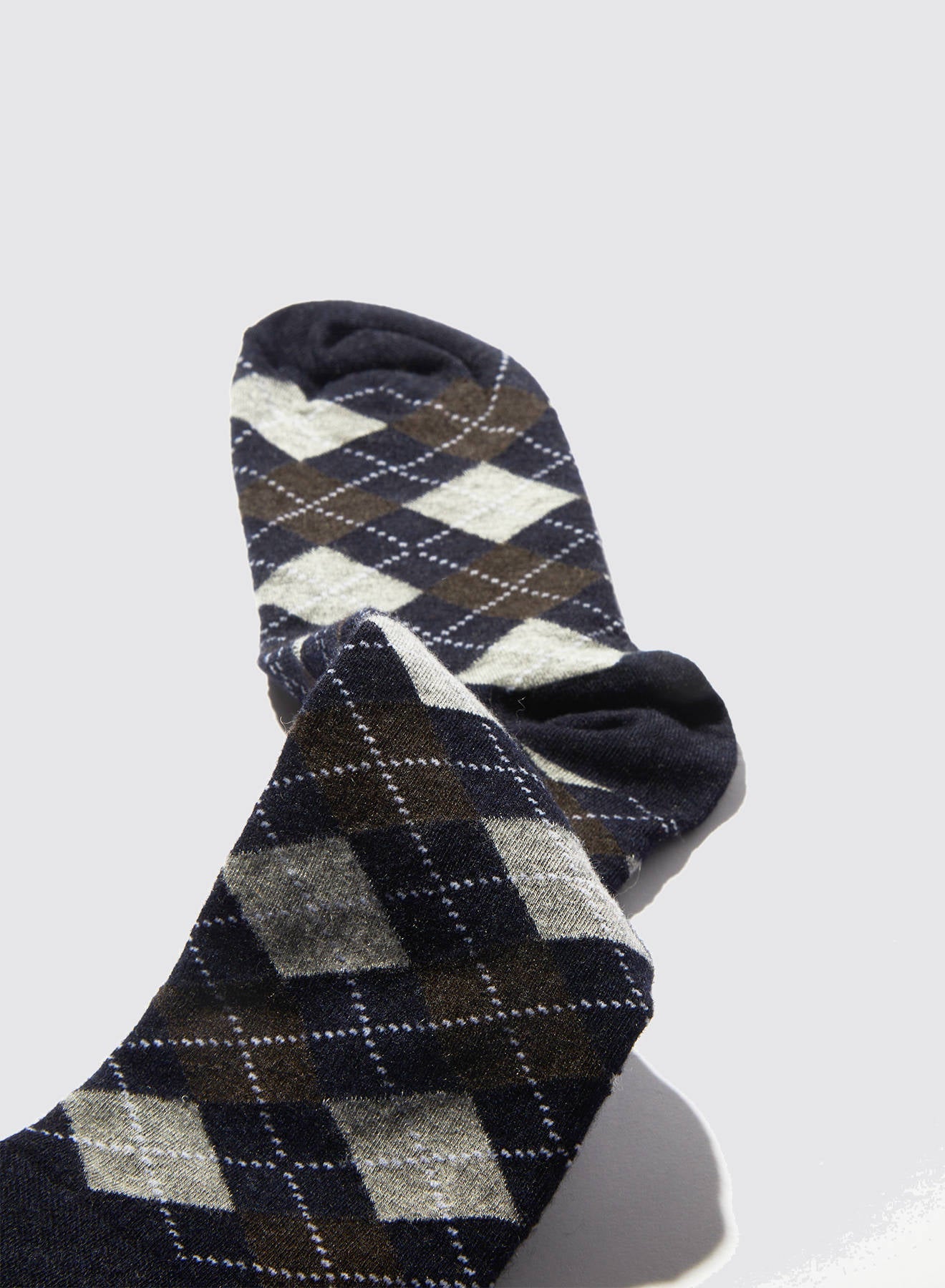 Maria La Rosa’s Harlekin Socks, expertly crafted in Italy from luxurious cashmere, feature elegant dark blue, gray, and brown argyle patterns and are displayed on a light gray background.