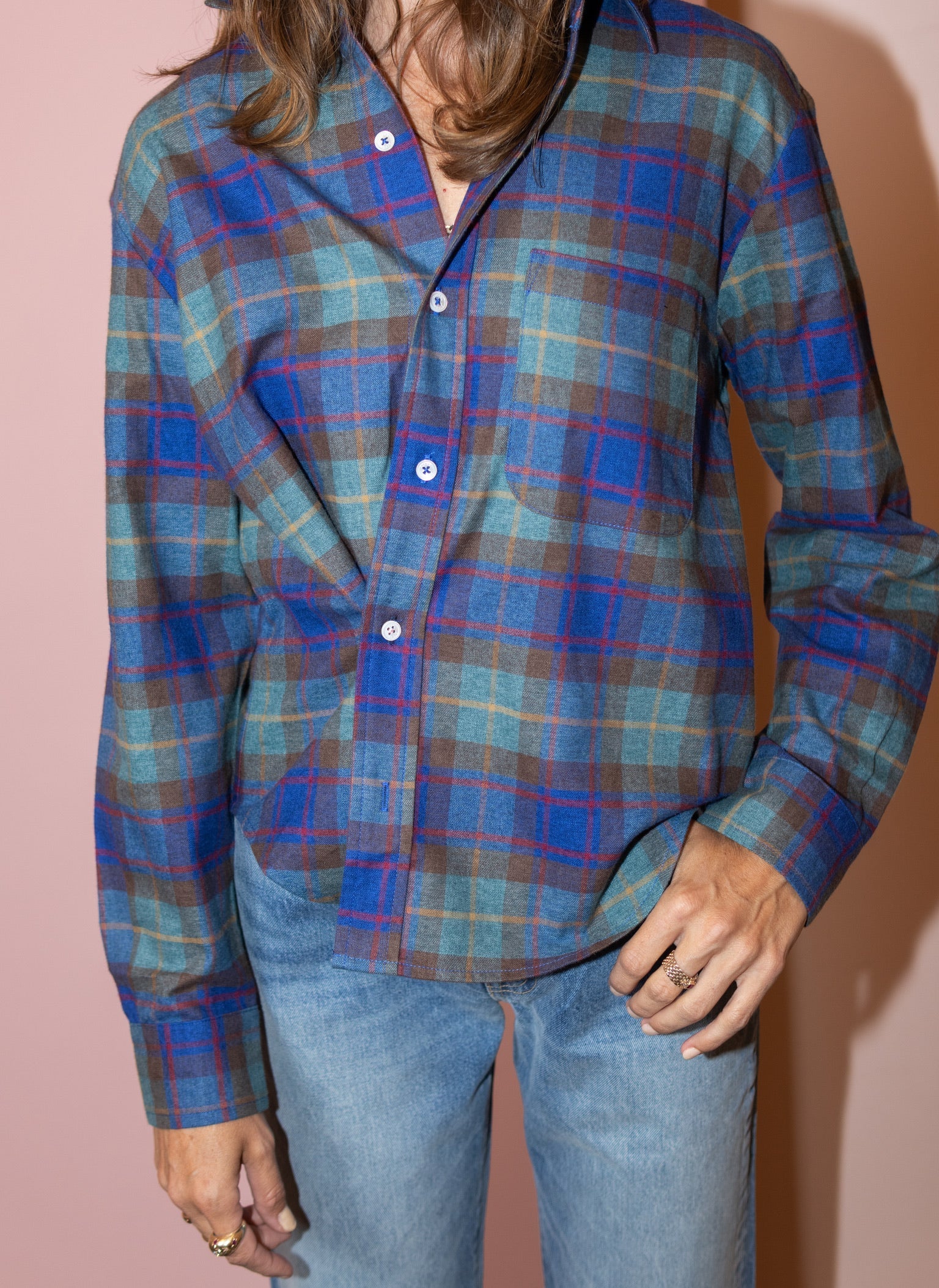 Blue plaid Cissa The Daily Shirt styled with light blue jeans, set against a pink background for a modern look.