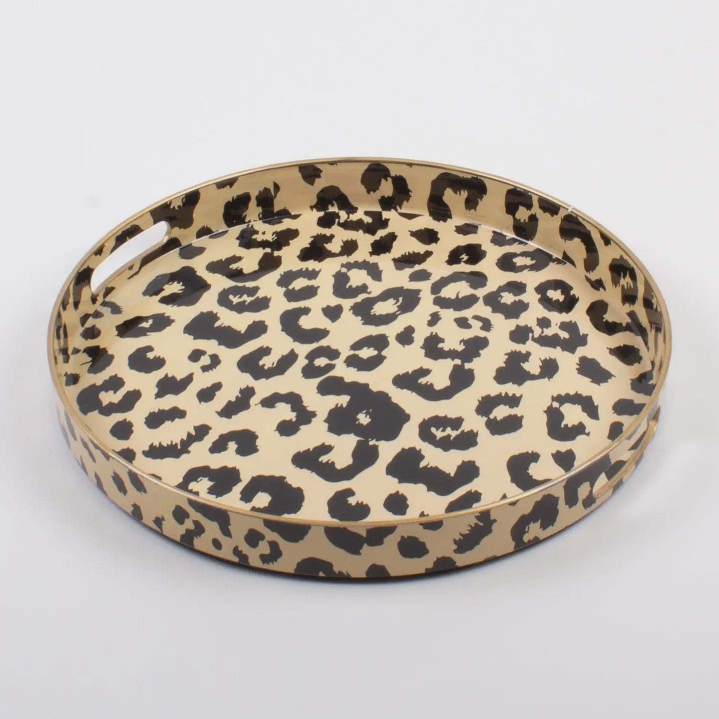 The Faire Leopard Round Tray features an elegant design, boasting a black and brown animal print pattern on a light background. It is crafted with a smooth, glossy finish and enhanced by a raised edge and built-in side handles for effortless elegance.