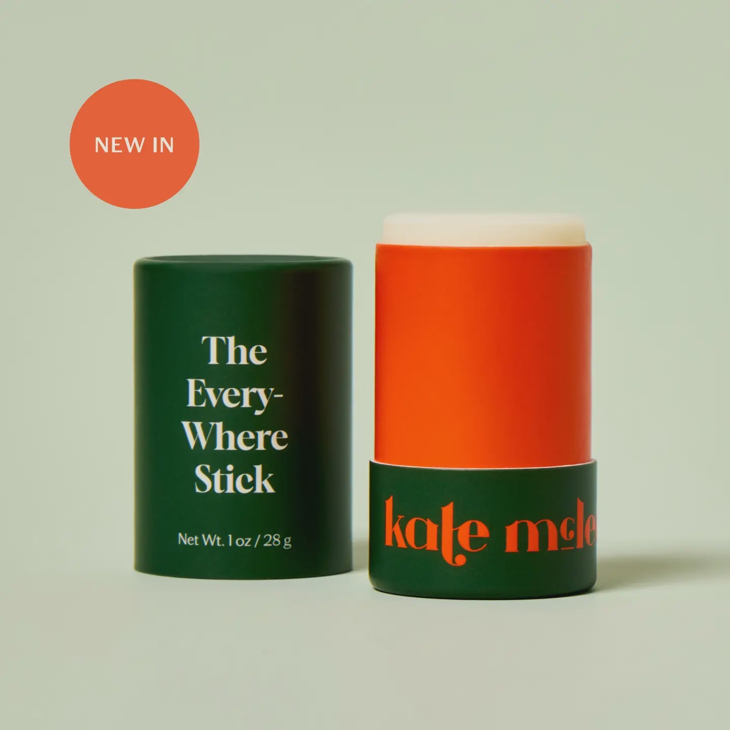 An orange and green tube of "The Everywhere Stick" by Faire with its cap off reveals the wax-free formula. A "NEW IN" label is on display, and the packaging boasts bold, modern text, infused with plant butters.