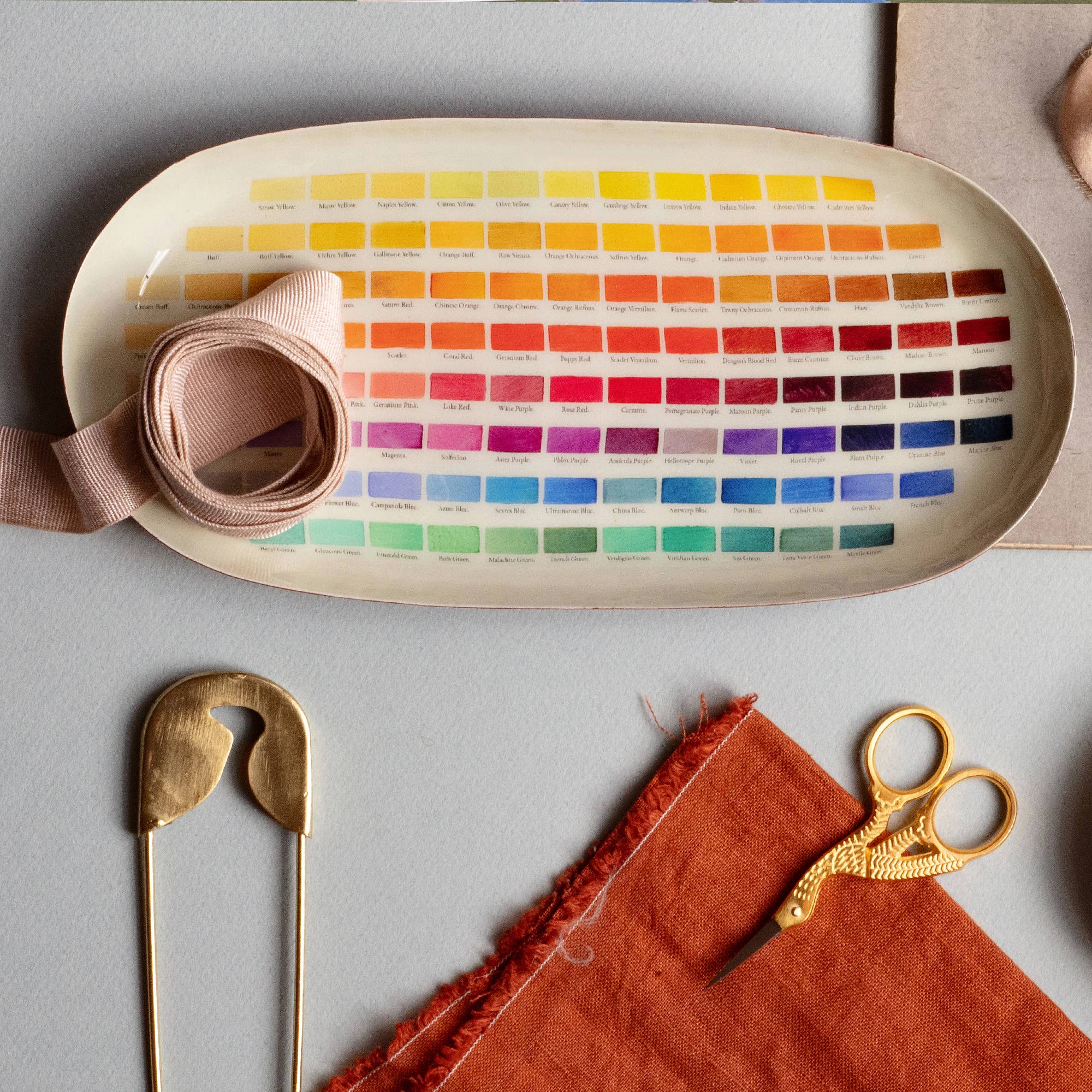 Oval enamel tray by Bungalow Furniture displayed with sewing accessories on a gray surface for a chic workspace look.