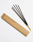 A brown rectangular box labeled "PFC Incense Sticks" by Faire rests beside four yellow-tipped incense sticks arranged in a fan shape on a white background.