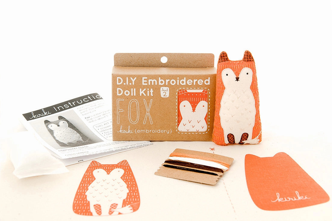 The Faire Fox Embroidery Kit includes screen-printed fabric, felt pieces, embroidery thread, instructions, and a sample fox doll—all artfully displayed on a white background.