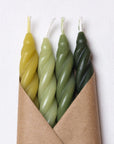The Woodland Spiral Beeswax Candles S/4 by Faire features four handcrafted candles in yellow and green shades, wrapped in brown paper—thoughtfully made in the Catskills, NY.