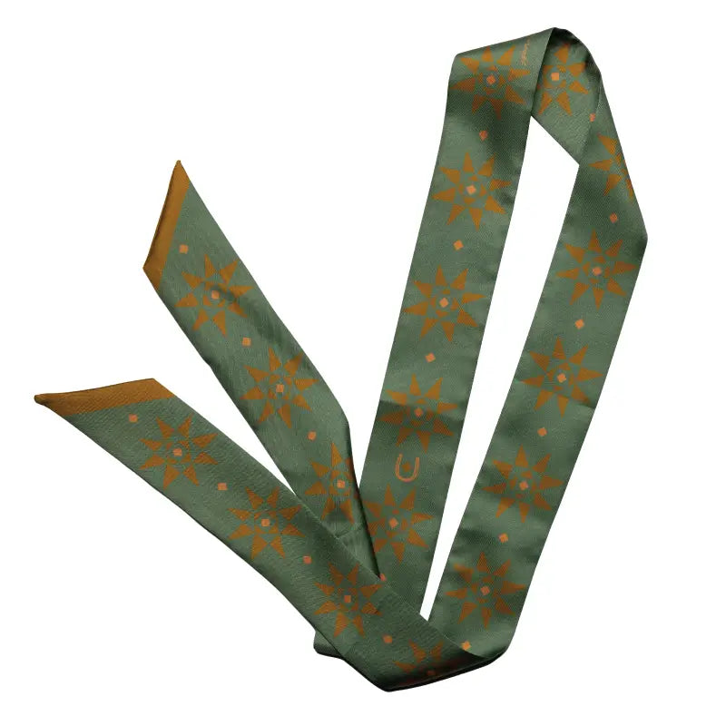 The Faire Twilly Scarf features green silk with orange starburst and diamond patterns, a small horseshoe design, pointed ends, and a gold-toned reverse—making it the perfect gift for any special occasion.