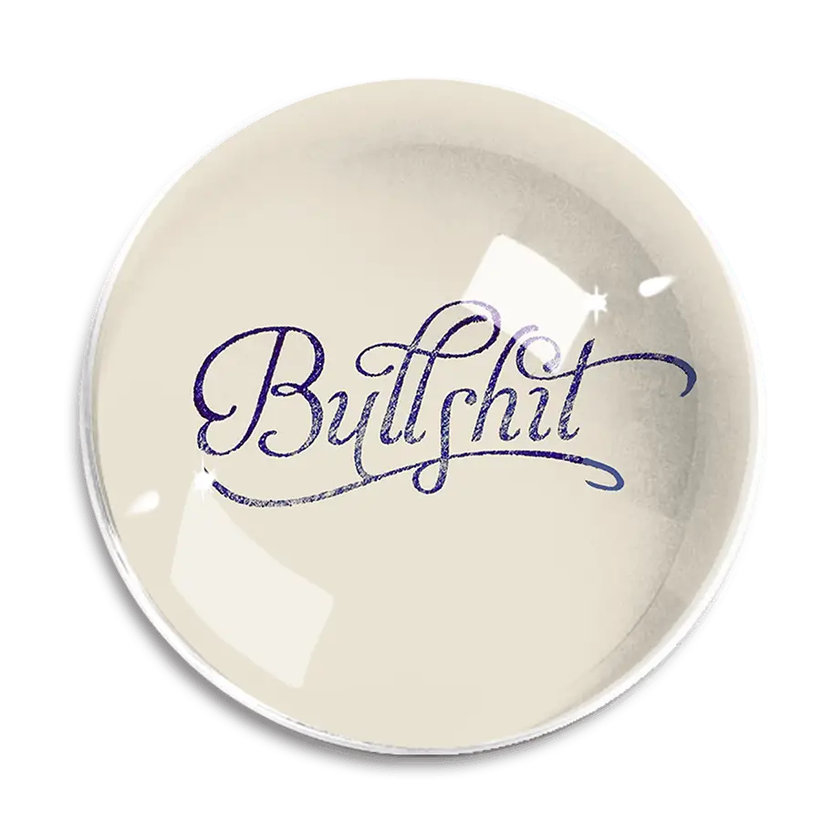 The Dome Crystal Paperweight by Ben's Garden, handcrafted in a New York studio, features the word "Bullshit" elegantly written in cursive blue lettering at its center.
