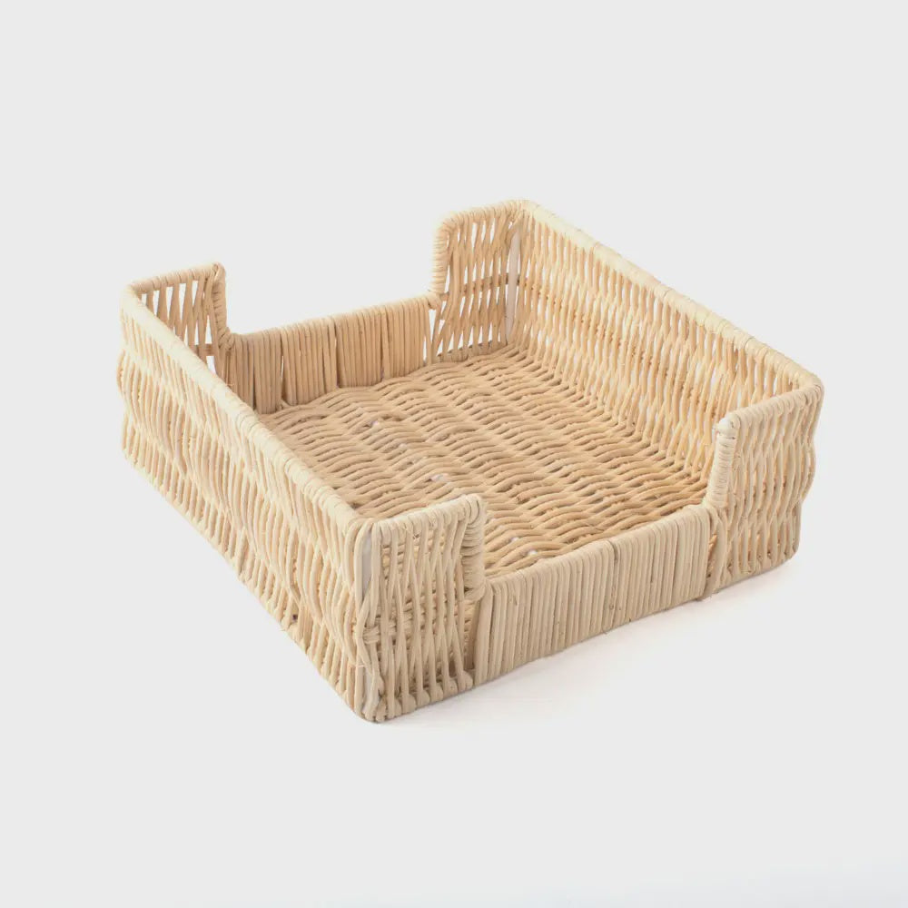 The Rattan Bev Napkin Tray by Faire is a square, handcrafted wicker basket featuring slightly raised sides and an open-top design, making it a charming holder for cocktail napkins. Made from natural rattan, its light beige hue contrasts beautifully against a plain white background.