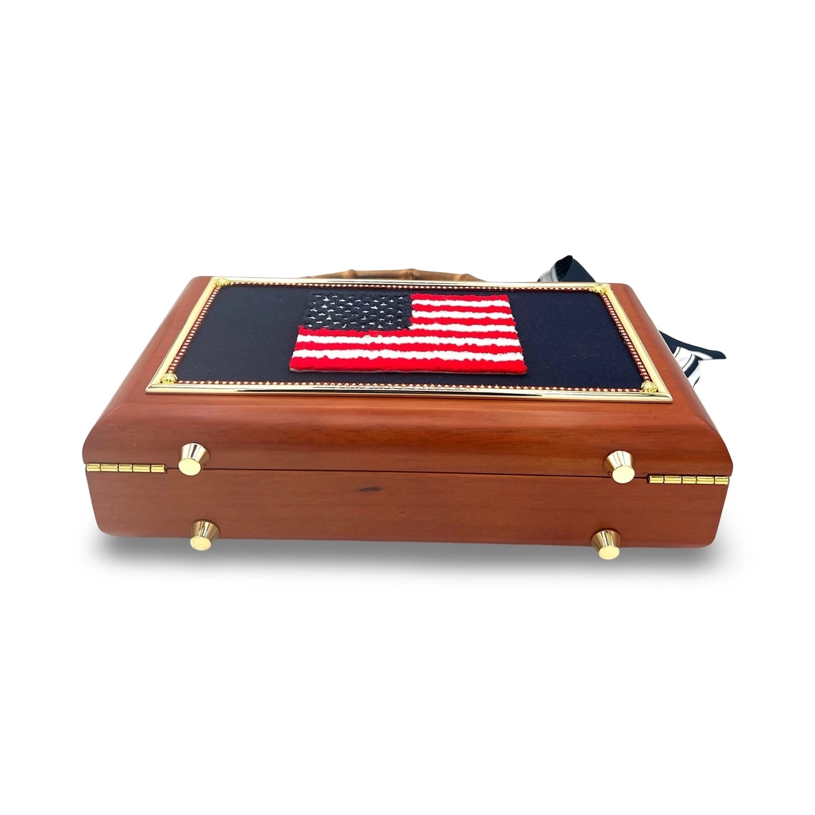 The Grand Old Flag Bag by Faire features a beaded chenille American flag patch on the lid and gold-accented wooden construction, shown against a white background.