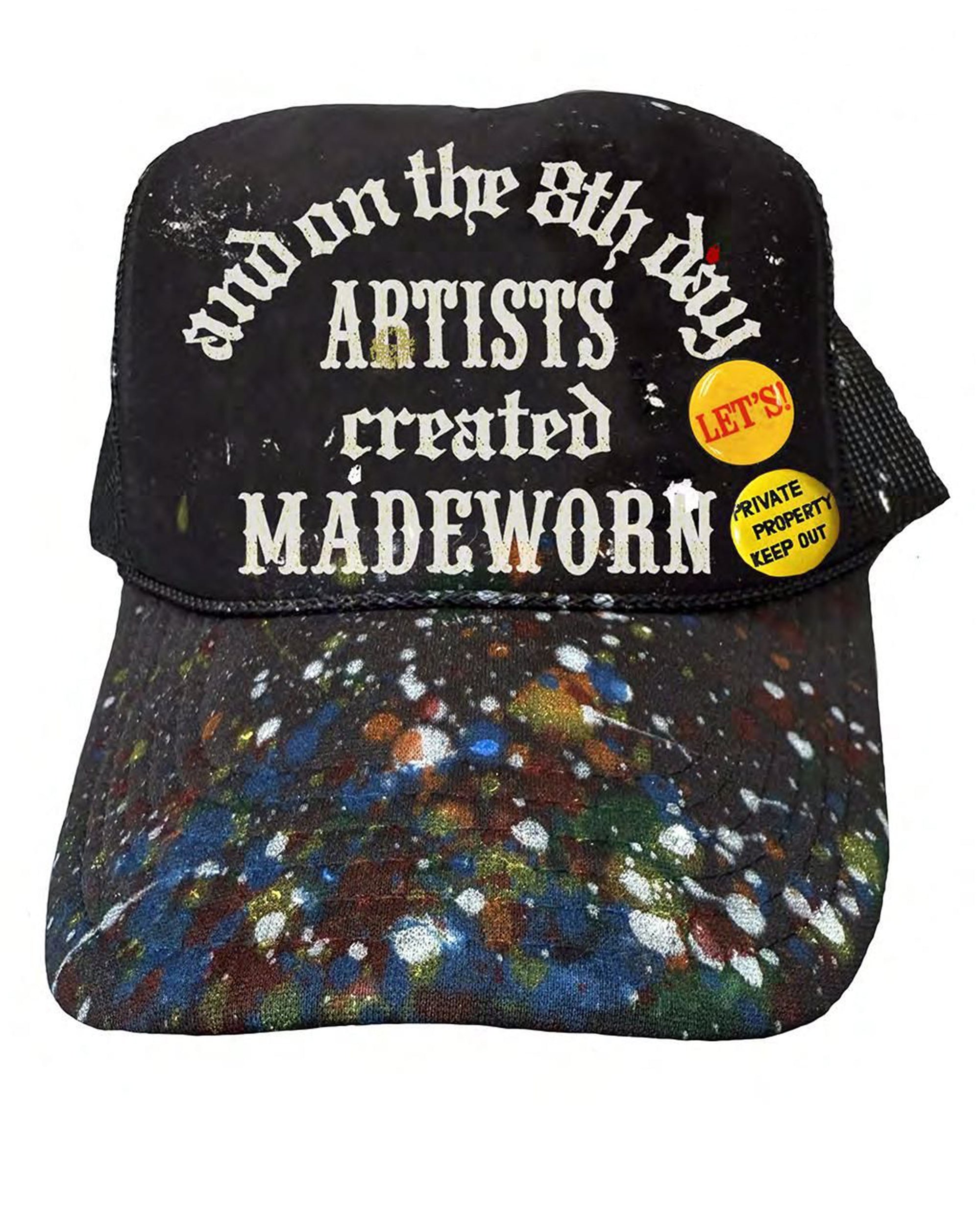The Made Worn 8th Day Artist Hat is a hand-painted black trucker hat with colorful paint splatters, "and on the 8th day ARTISTS created MADEWORN" text, and two yellow pins that say “LET'S!” and “PRIVATE PROPERTY KEEP OUT.”.