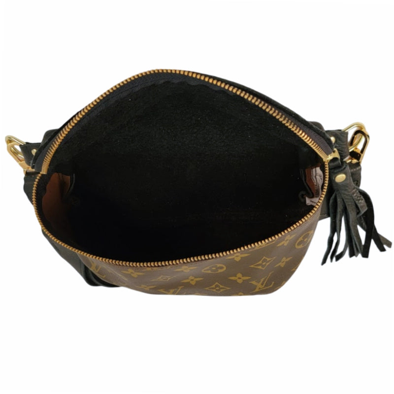 Open view of the Faire Britt Belt Bag in black leather, featuring gold zipper and hardware, black interior, tassel detail, and a monogram exterior that blends sustainable luxury with timeless style.