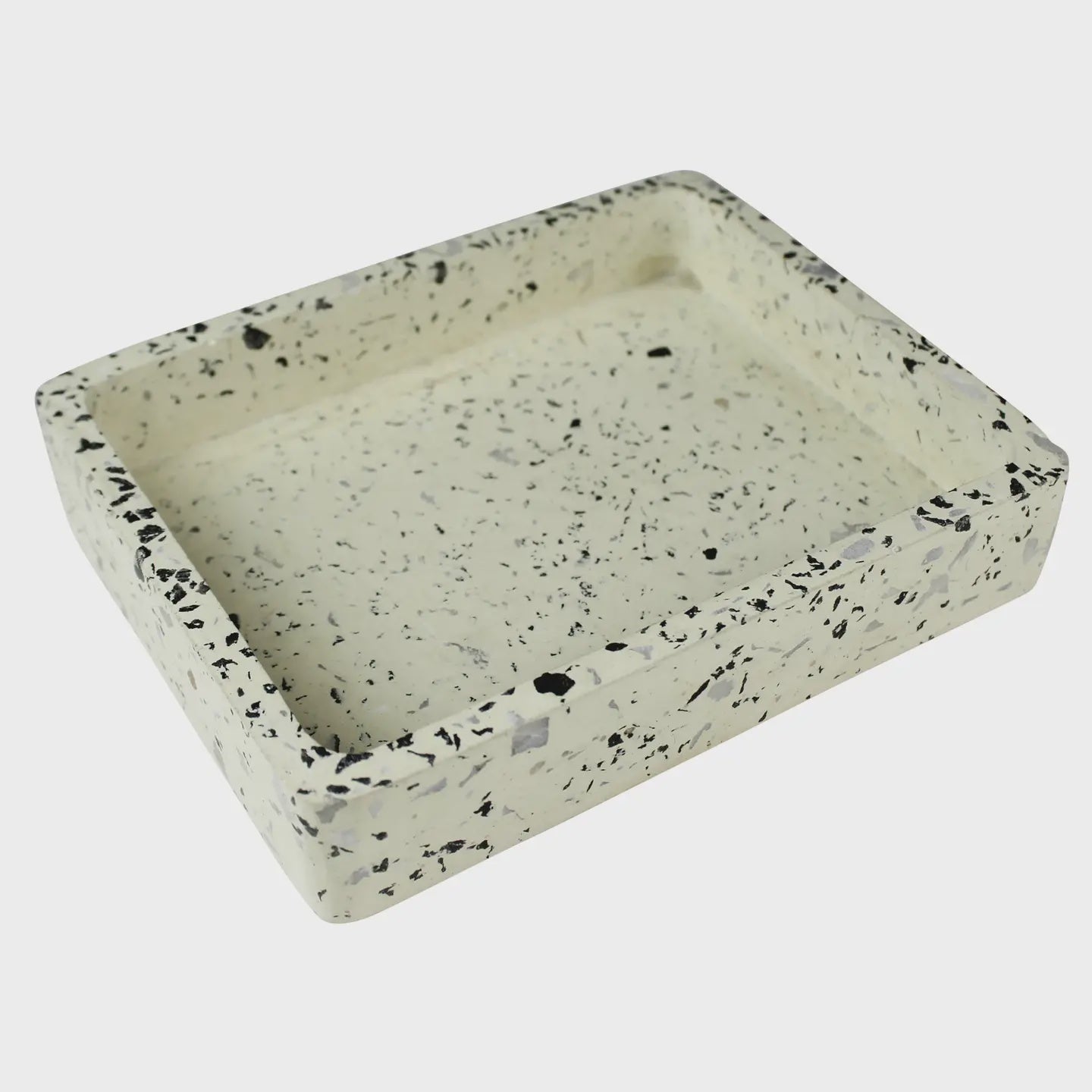 The HomArt Terrazzo Tray White is a rectangular tray with raised edges, showcasing black, gray, and quartz specks on a light beige base. It's elegantly displayed against a plain white backdrop.