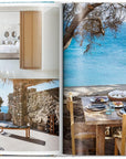 A spread from Great Escapes Greece The Hotel Book by Ingram Book Company displays a bright bedroom, a home gym with stationary bike, and a rustic outdoor dining area overlooking stunning rocky coastline and blue sea views.