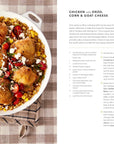 A skillet of golden-brown chicken thighs with orzo, corn, and cherry tomatoes, topped with goat cheese and parsley—this comforting family meal from Every Day With Babs by Random House is pictured beside a recipe page on a checkered cloth.