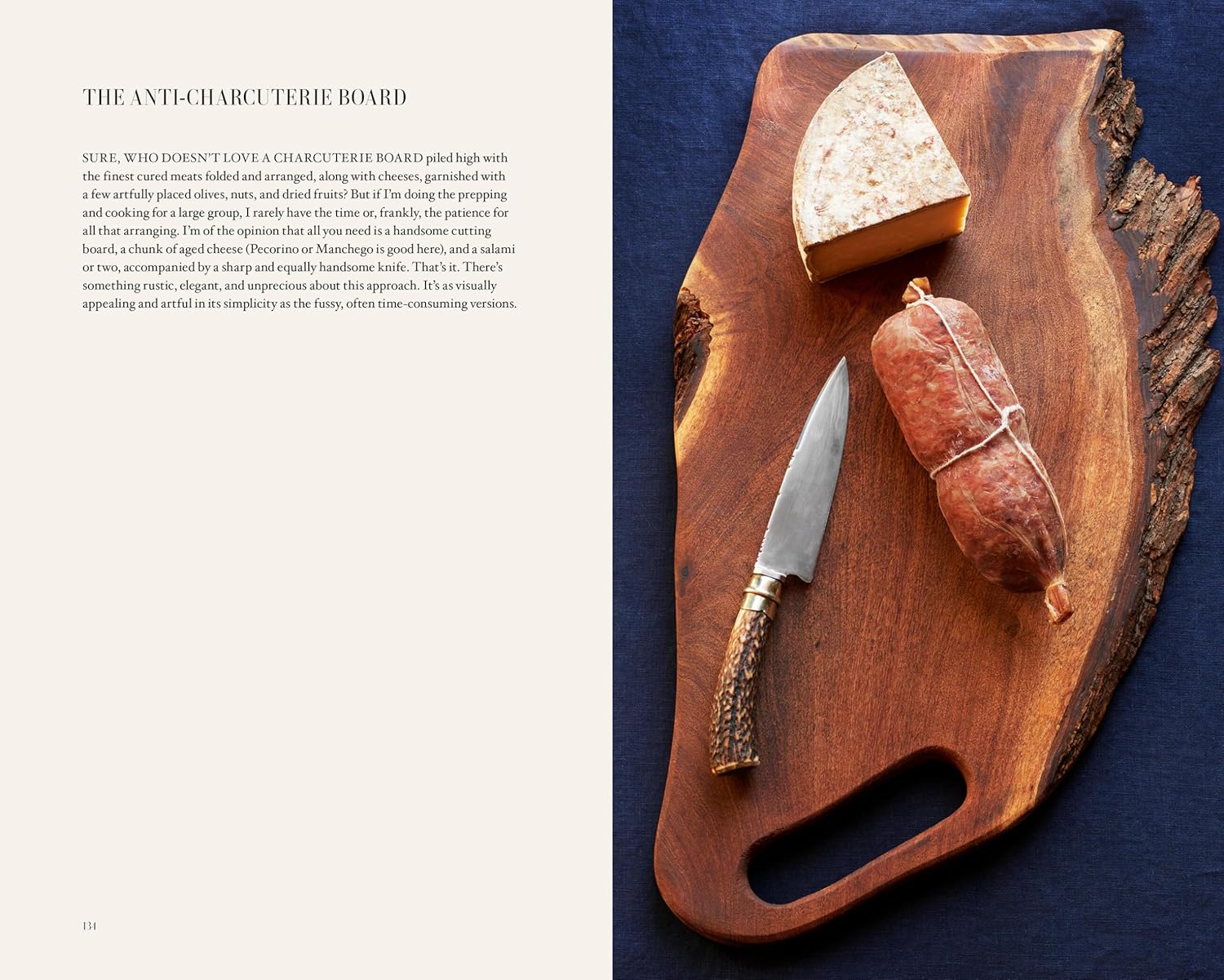A rustic wooden board with cheese, an antler-handled knife, and cured sausage rests on a dark blue surface. Text highlights an "anti-charcuterie board" and simple recipes from A Man & His Kitchen by Hachette Book Group on the left.