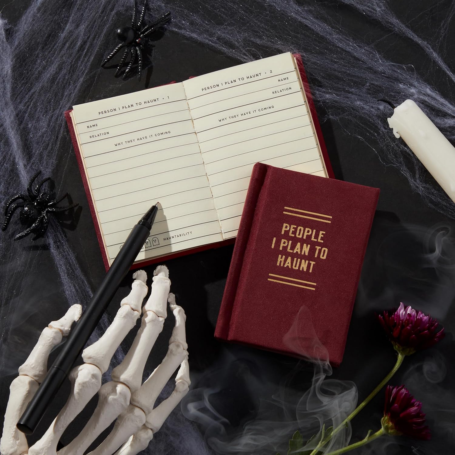 “People I Plan to Haunt” diary by Hachette on a desk with skeleton hand, styled with spooky stationery accessories.