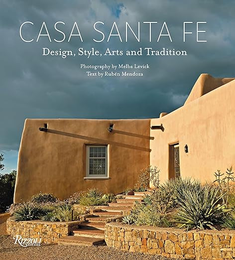 Cover of 'Casa Santa Fe' by Random House, featuring an adobe brick structure that captures the essence of Southwestern style. The scene includes a gracefully curved staircase, surrounded by desert plants under a clear blue sky, exhibiting influences from Native American design. The cover text includes the names of both the author and photographer.