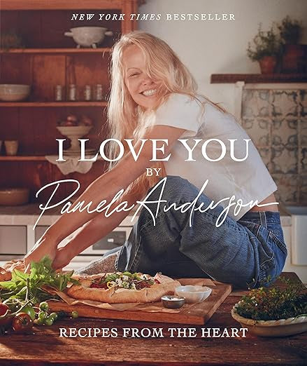 Cover of the bestseller "I Love You Recipes" published by Hachette Book Group. A woman in a casual outfit smiles while sitting on a kitchen counter, surrounded by fresh ingredients and bread, highlighting her expertise in plant-based cooking.