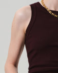 A model wears the Isabel Rib Tank F25 by Citizens Of Humanity/AGOLDE—a sleeveless, high neckline, ribbed dark burgundy top crafted from supportive cotton—paired with a chunky gold chain necklace against a light gray background.