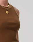 A person wears the Isabel Rib Tank F25 by Citizens Of Humanity/AGOLDE, a brown ribbed cotton sleeveless top with a high neckline, paired with two layered gold necklaces against a plain light background.