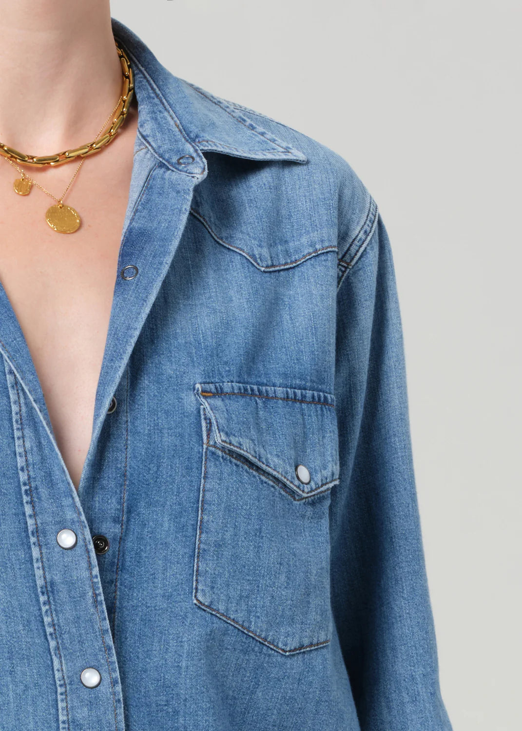 A person wears a Citizens Of Humanity/AGOLDE cropped western shirt with a front pocket and gold necklaces with round pendants, shown from shoulders to chest against a plain background.