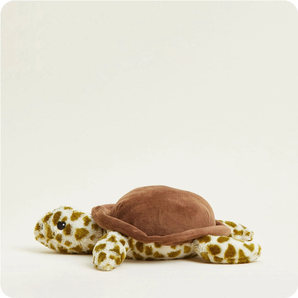 Faire’s Turtle Warmies is a plush turtle toy with a soft brown shell and yellow-and-white patterned limbs and head, providing sensory comfort as it rests on a plain light background.