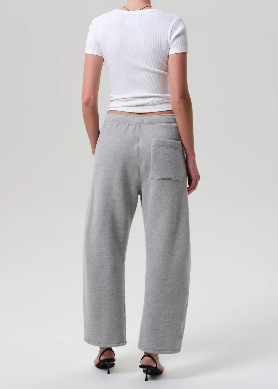 Heather grey Citizens Of Humanity Miro Sweatpant styled with a white tee and black heeled sandals, shown from the back.